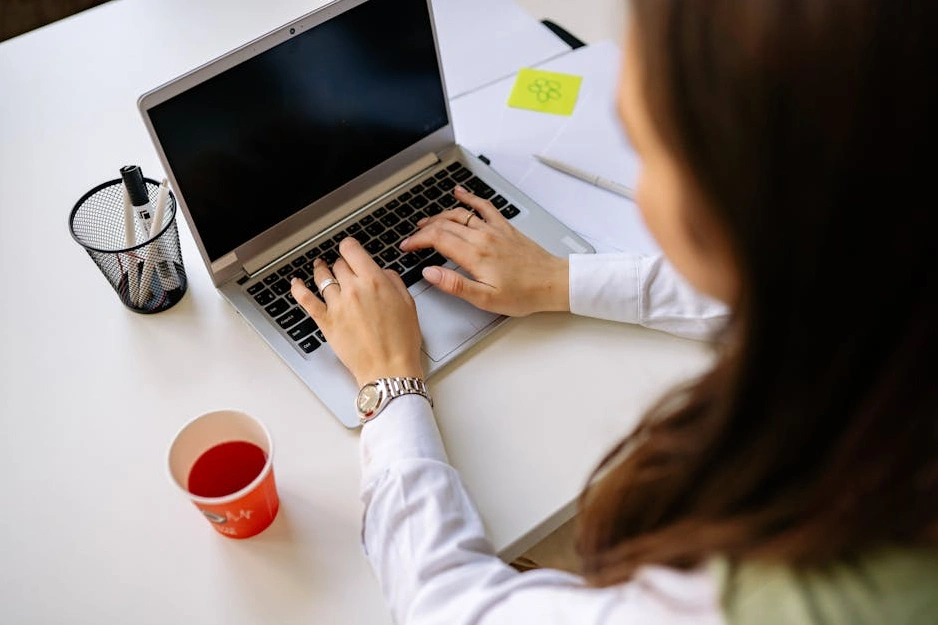 Professionista del marketing che scrive contenuti su un laptop in un ufficio moderno.